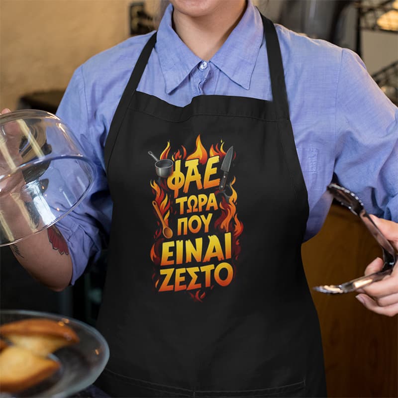 Μαύρη ποδιά μαγειρικής με τσέπες και αστεία στάμπα ''Φάε τώρα που είναι ζεστό''